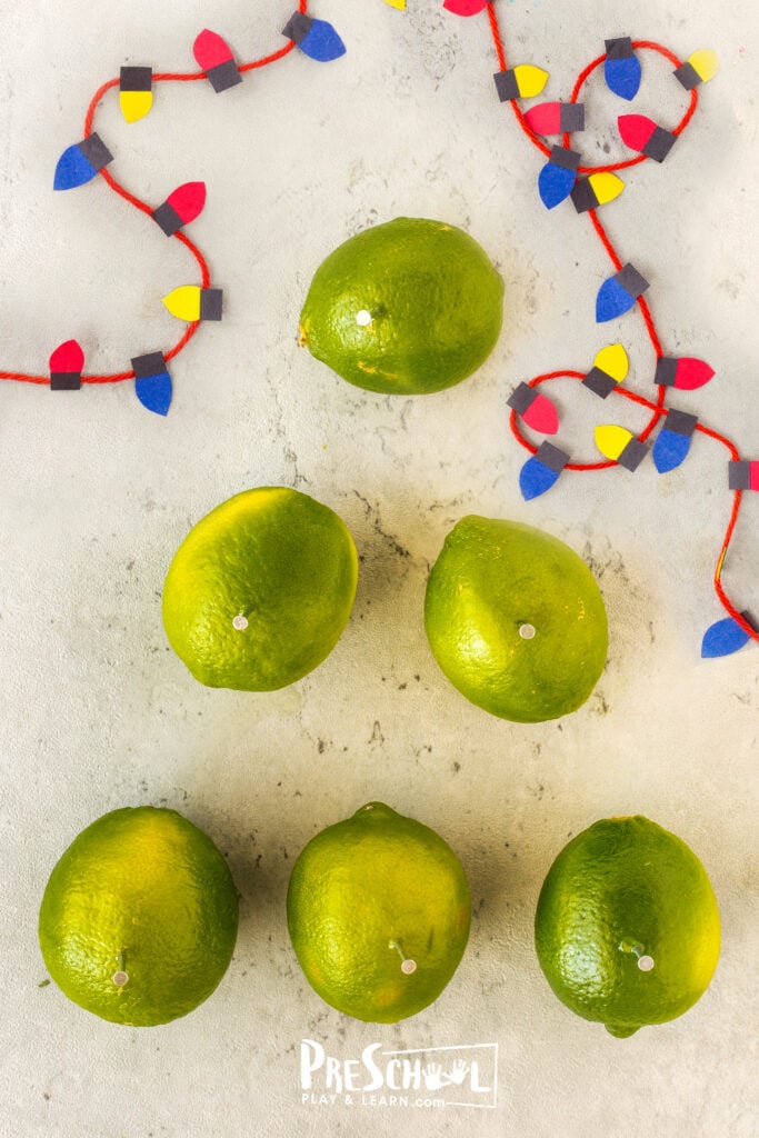 The second step is to stick a nail about halfway in each of the lime fruits.